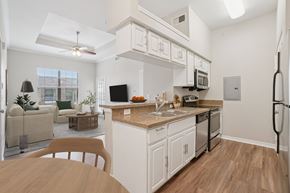 Lewisville apartment for rent - A kitchen with white cabinets and a wooden table.