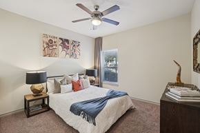 Farmers Branch apartment for rent - A bedroom with a bed, a ceiling fan, and a painting on the wall.