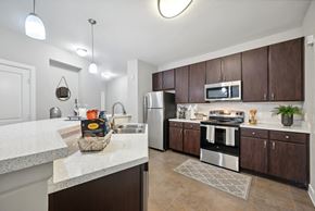 Dallas apartment for rent - A kitchen with brown cabinets and a white counter.