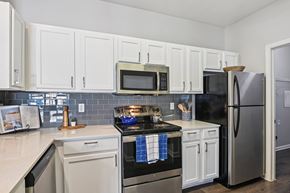 Fort Worth apartment for rent - A kitchen with white cabinets and a black stove top.