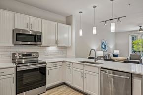 Forney apartment for rent - A modern kitchen with white cabinets and stainless steel appliances.