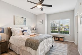 Fort Worth apartment for rent - A bedroom with a large bed and a window overlooking a parking lot.