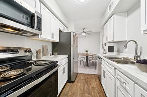Oklahoma City apartment for rent - A modern kitchen with white cabinets and a black stove top.