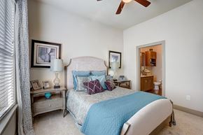 Euless apartment for rent - A bedroom with a bed, nightstand, and a ceiling fan.