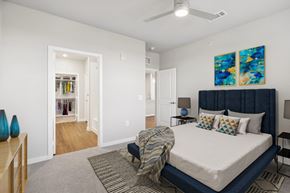 Katy apartment for rent - A bedroom with a bed, a ceiling fan, and a painting on the wall.