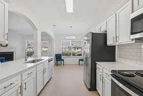 Waxahachie townhouse for rent - A kitchen with white cabinets and a black refrigerator.