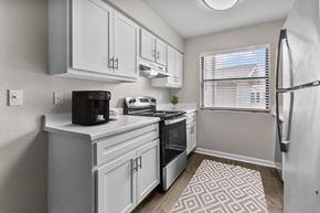 Oklahoma City apartment for rent - an open kitchen with white cabinets and a window and a refrigerator