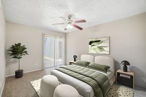 Mesquite apartment for rent - A bedroom with a bed, a plant, and a painting on the wall.
