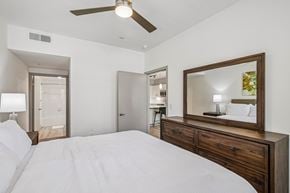 Forney apartment for rent - A bedroom with a large bed, a ceiling fan, and a mirror with a wooden frame.