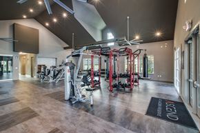 Conroe apartment for rent - a spacious fitness center with exercise equipment and a large screen on the wall