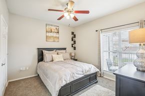 Houston apartment for rent - A bedroom with a bed, a ceiling fan, and a painting on the wall.