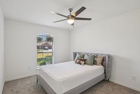 Waxahachie townhouse for rent - A bedroom with a bed, pillows, and a ceiling fan.