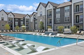 Fort Worth apartment for rent - A pool surrounded by lounge chairs and buildings in the background.