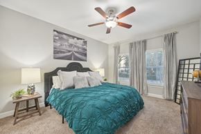 Dallas apartment for rent - A bedroom with a bed, a ceiling fan, and a painting on the wall.