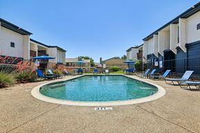 Denton apartment for rent - A swimming pool surrounded by lounge chairs in a residential area.