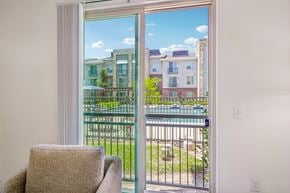 Forney apartment for rent - A chair sits in a room with a view of a pool and apartment buildings outside.