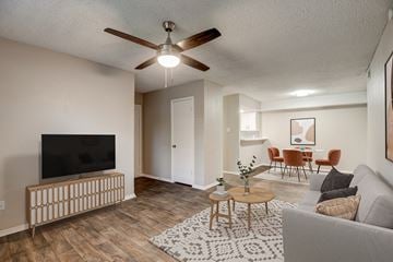 Hurst apartment for rent - an open living room and dining room with a ceiling fan and a tv