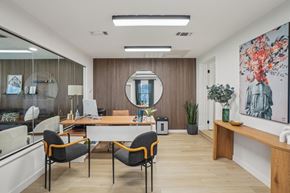 Denton apartment for rent - A modern office space with a wooden desk, two chairs, and a large mirror on the wall.