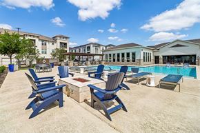 Waxahachie apartment for rent - A poolside area with blue chairs and a table.