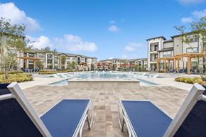 Katy apartment for rent - A swimming pool surrounded by a stone patio and lounge chairs.