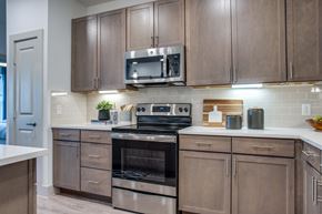 Burleson apartment for rent - Stainless range and microwave framed by wood cabinetry and tile backsplash.