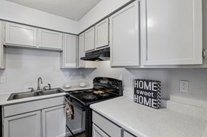 Austin apartment for rent - A kitchen with white cabinets and a black stove top.