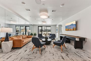 Austin apartment for rent - A modern living room with a large couch, chairs, and a painting on the wall.