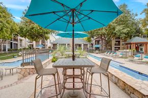 New Braunfels apartment for rent - a patio with tables and umbrellas next to a swimming pool