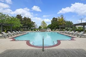 Fort Worth apartment for rent - A large pool surrounded by lounge chairs and trees.