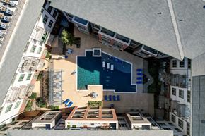 Euless apartment for rent - A swimming pool is surrounded by a small building and a parking lot.