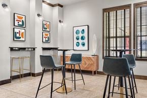 Buda apartment for rent - Social nook with bar-height tables, modern stools, and framed artwork accents.