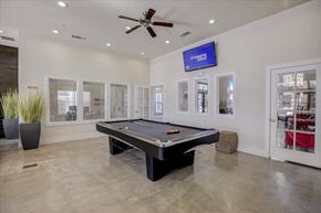 Kyle apartment for rent - Indoor game room with pool table, wall-mounted TV, and polished concrete floors.
