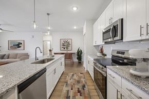 Farmersville apartment for rent - A modern kitchen with white cabinets and granite countertops.