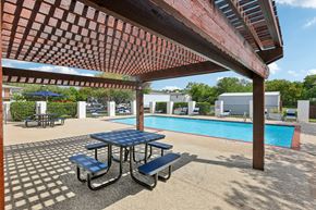 Austin apartment for rent - A picnic table with a blue top is in the foreground of a pool area.