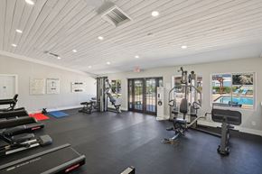 Clearwater apartment for rent - A spacious gym with a variety of equipment and a view of the pool outside.