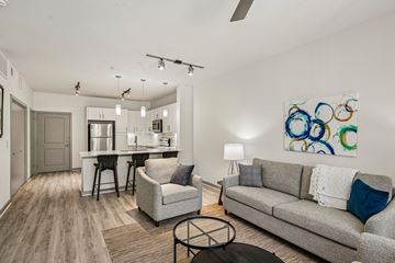 Forney apartment for rent - A modern living room with a grey couch, a white coffee table, and a painting on the wall.