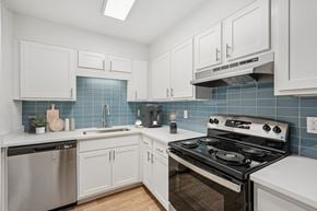 Venice apartment for rent - A kitchen with white cabinets and a black stove top oven.