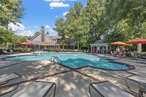 Bartlett apartment for rent - a resort style pool with chairs and umbrellas and a building in the background