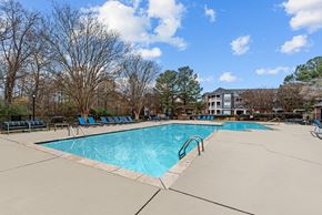 Memphis apartment for rent - A large swimming pool surrounded by trees and chairs.