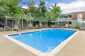 Lakewood apartment for rent - A large swimming pool surrounded by a fence and trees.