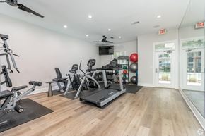 Denton apartment for rent - A well-equipped gym with a variety of exercise machines and a ceiling fan.