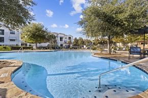 Kyle apartment for rent - A swimming pool surrounded by trees and a building in the background.