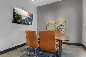 San Antonio apartment for rent - Two orange chairs are placed in front of a table with a painting and a picture on the wall.
