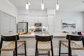 Waxahachie apartment for rent - a kitchen with a marble counter top with three stools