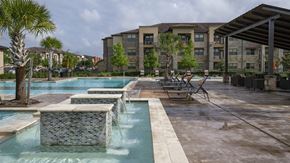 Pearland apartment for rent - a swimming pool with chairs and a building in the background