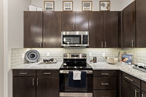 Fort Worth apartment for rent - A kitchen with brown cabinets and a stove top oven.