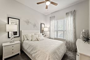 Fort Worth apartment for rent - A bedroom with a bed, nightstand, and a ceiling fan.