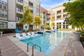 Fort Worth apartment for rent - A pool surrounded by chairs and trees in front of apartment buildings.