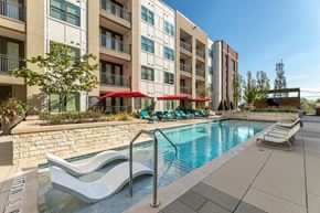 Plano apartment for rent - A swimming pool with lounge chairs and umbrellas.