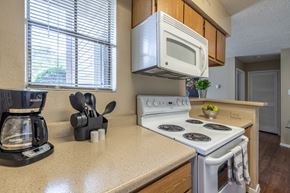 Austin apartment for rent - A kitchen with a white stove top oven and a white microwave above it.
